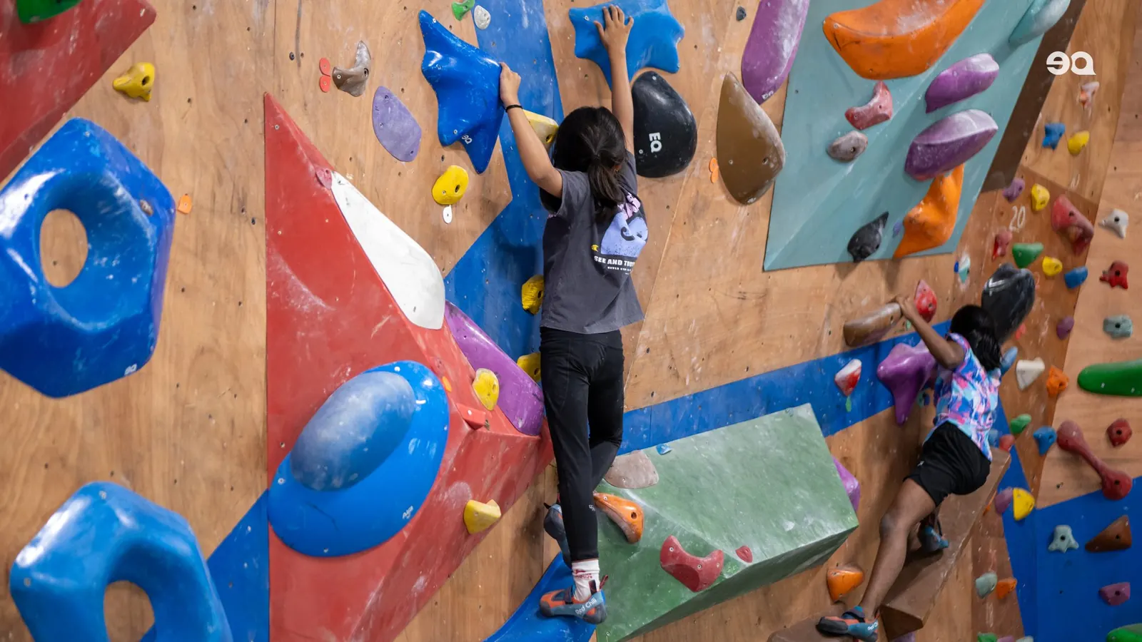 Two climbers on the colourful bouldering wall at Equilibrium Hoodi